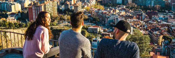 Three people sitting on ledge overlooking the city of Barcelona