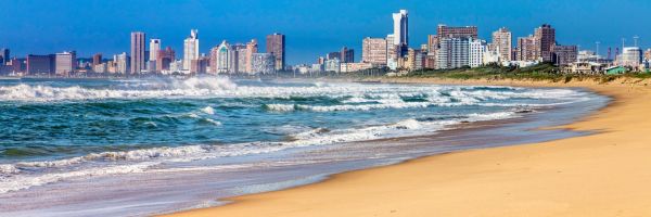City of Durban seen from a far-reaching beach with large, crashing waves