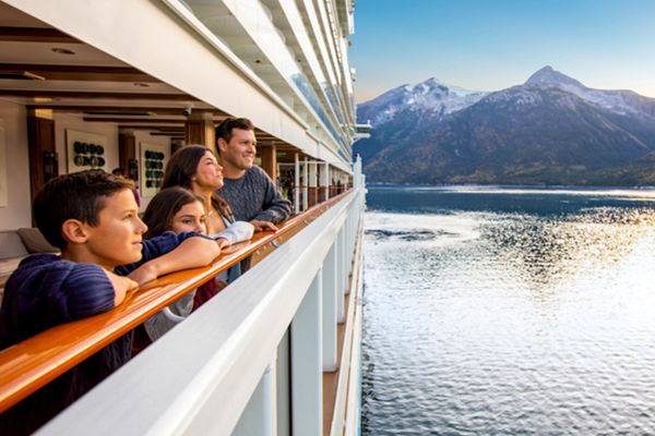 Family on the edge of a cruise ship looking out at mountains