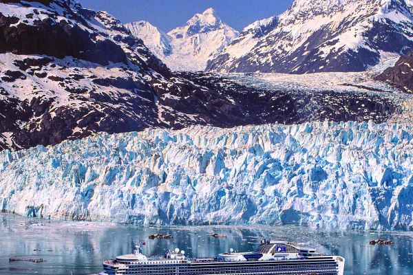 Wide shot of a cruise ship with ice and mountains in the background