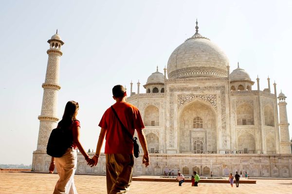 Couple holding hands in front of the Taj Mahal