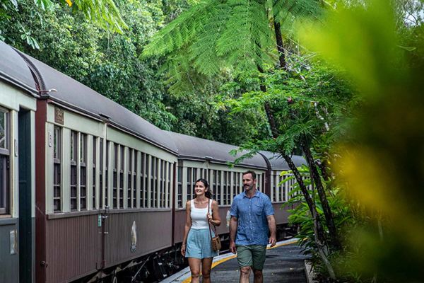Couple walking through a jungle while a train goes past