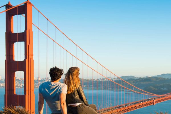 Couple sitting on a rock overlooking the Golden Gate Bridge