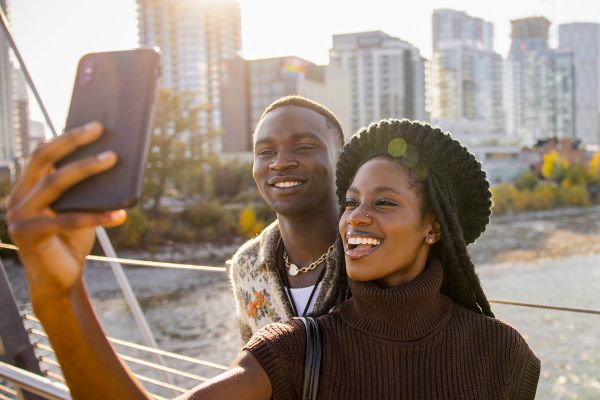 Couple taking a selfie with cityscape and water in the background