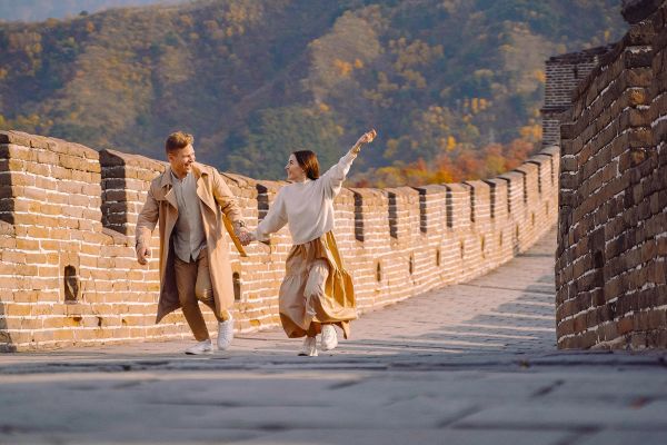 Couple hold hands running along the Great Wall of China