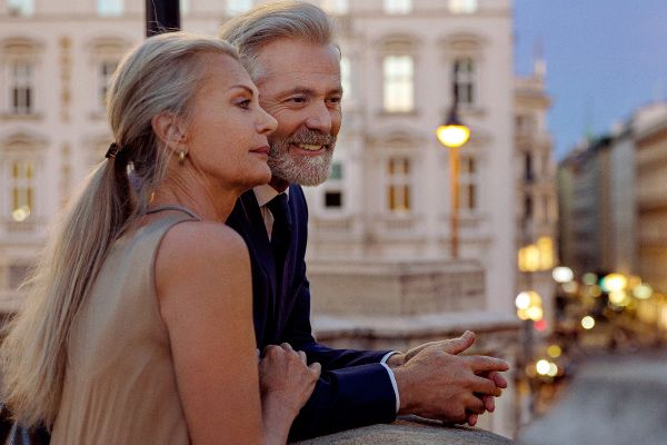 A couple leaning against a balustrade overlooking Vienna during the evening.