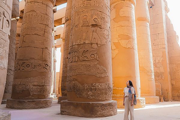 Woman standing next to large columns covered in hieroglyphics in Egypt