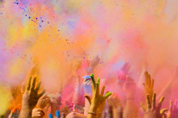 Shot of hands throwing colourful paint and dust at a colour festival