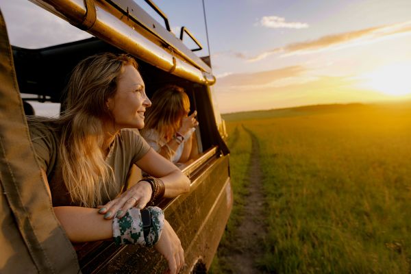 Women leaning out of a safari truck watching a sunset