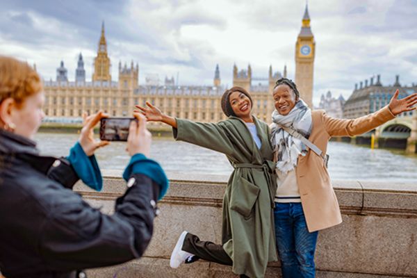 Two women posing for a picture with London's Parliament building in the background