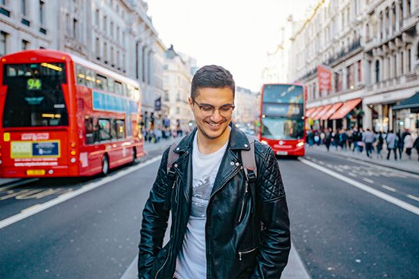Man in a leather jacket smiling in the middle of a city street in London