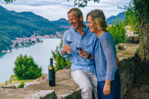 Elderly couple drinking wine overlooking a river and coastal town