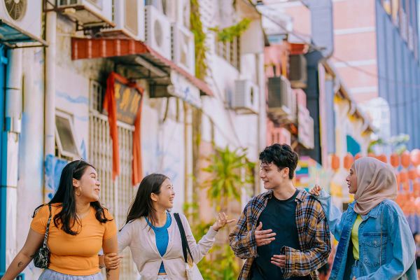 Man with a white backpack looking at a busy shopping street in Malaysia