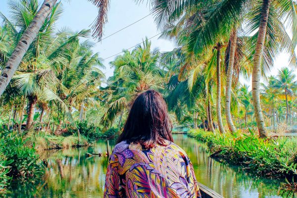 Woman sitting in a boat sailing past palm trees
