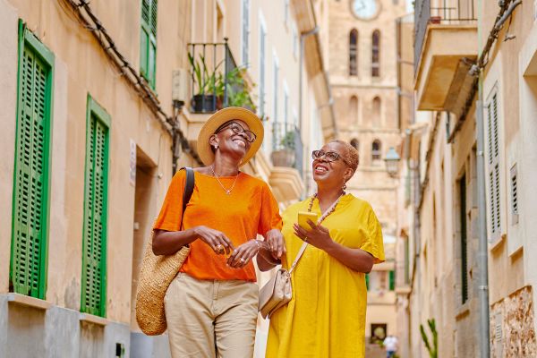 Two women smiling walking down a narrow street in Spain