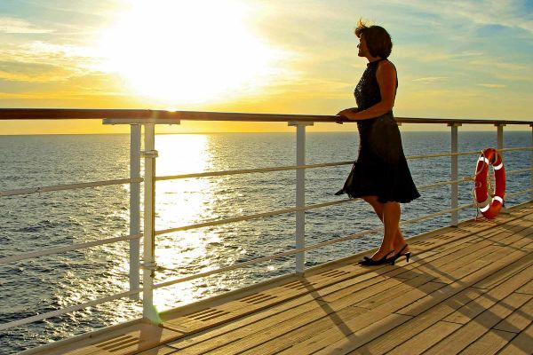 Lady looking over balcony at sunsetting above ocean