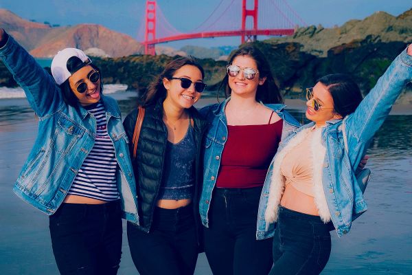 Four friends posing for a photo with the Golden Gate Bridge in the background