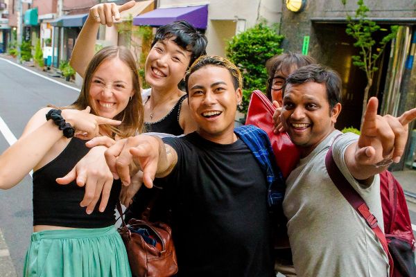 Friends pointing at a camera while taking a photo in a quiet, Japanese street