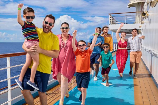 Family smiling while walking down outside deck of ship