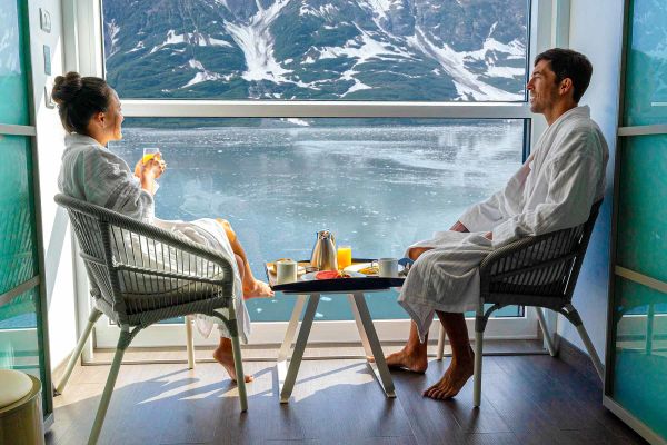 Two people sitting on their balcony looking at snow-capped mountains