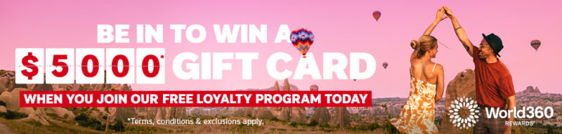Couple dancing beneath hot air balloons over a scenic valley featuring a chance to win a $5000 gift card when you join our free loyalty program