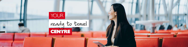 Your ready to travel centre - Asian businesswoman on a red chair waiting at an airport holding a tablet