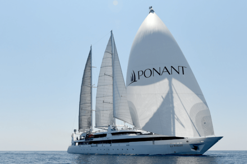 A large yacht with the word 'PONANT" emblazoned on its spinnaker