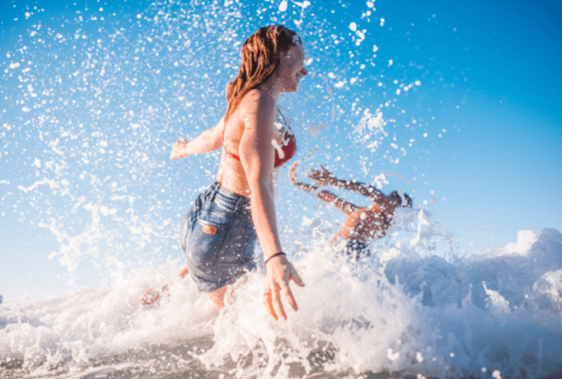 A couple splashing and jumping into the surf.