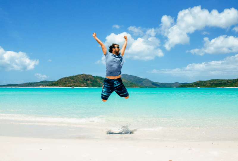 A man jumps for joy on Whitehaven Beach, Whitsunday Island