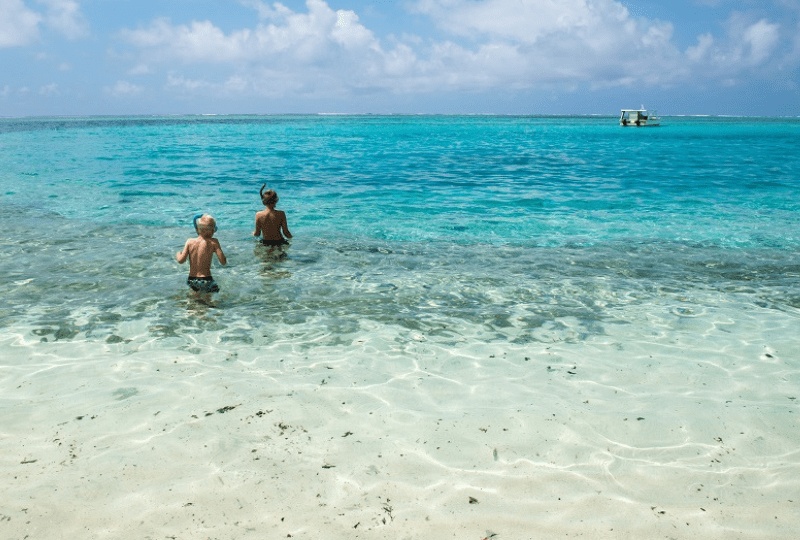 Two boys wade into still waters in Vanuatu to go snorkelling